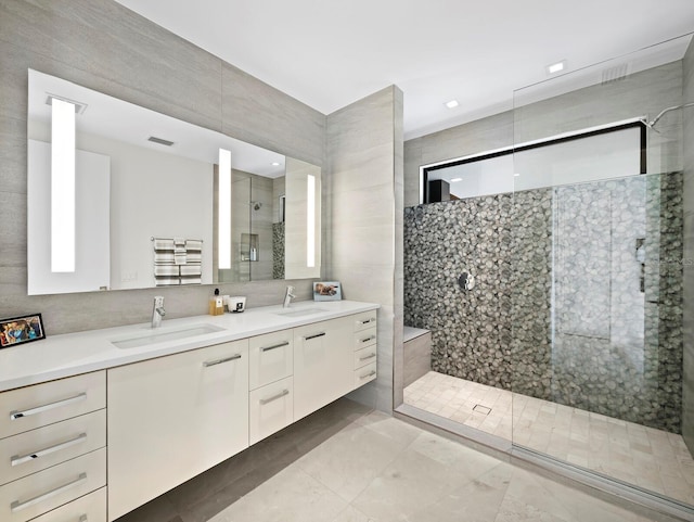 bathroom with visible vents, a sink, a tile shower, and double vanity