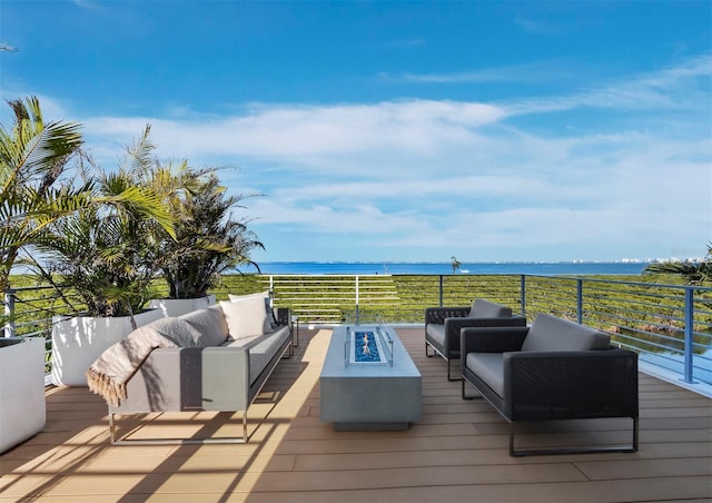 wooden deck with an outdoor living space with a fire pit and a water view