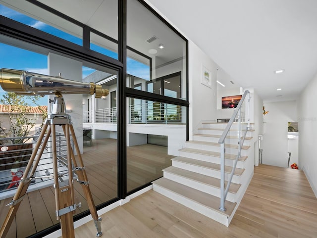 stairway featuring a wealth of natural light, visible vents, and wood finished floors