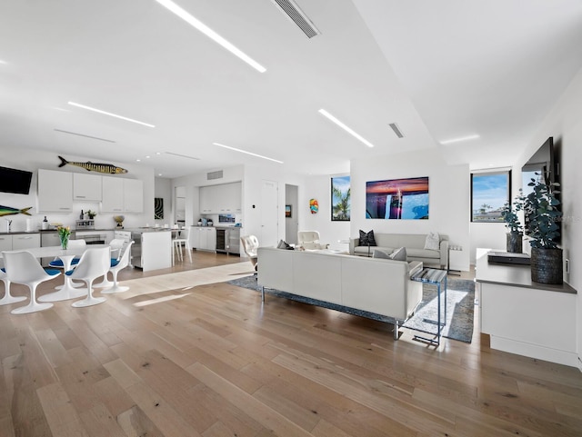 living room with light wood finished floors, visible vents, and a wealth of natural light