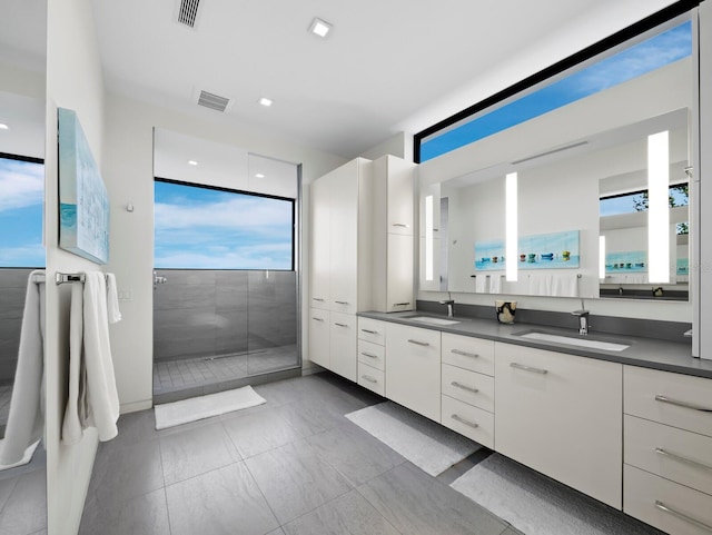 full bath featuring double vanity, visible vents, a sink, and a walk in shower