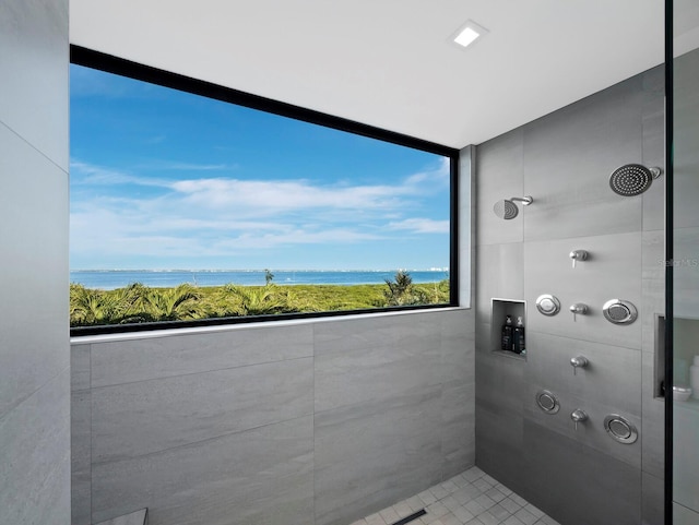 bathroom featuring tiled shower and a water view