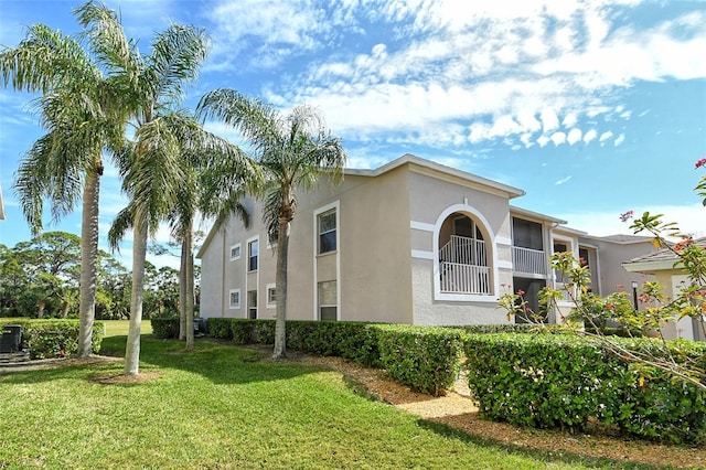 view of side of property featuring a lawn and stucco siding