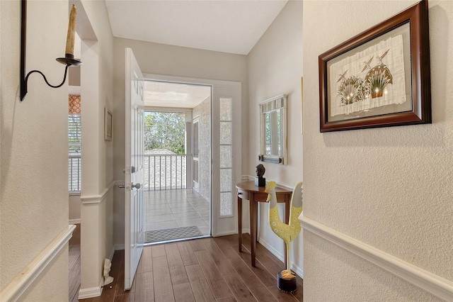 doorway featuring a textured wall, dark wood finished floors, and baseboards