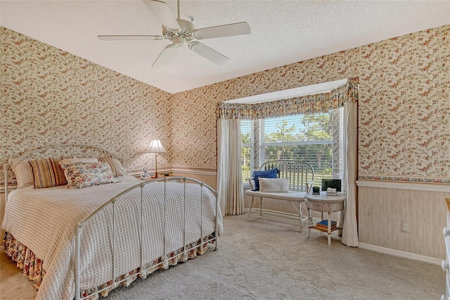 bedroom featuring a textured ceiling, carpet floors, wainscoting, and wallpapered walls