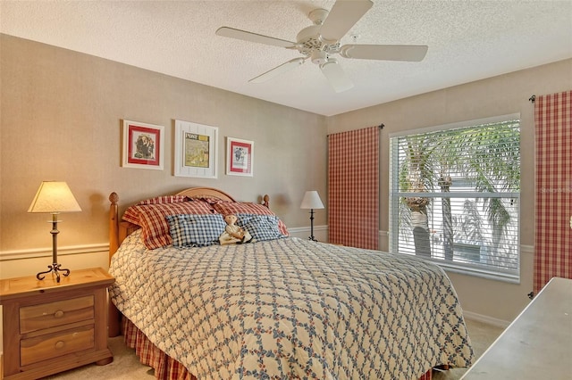 bedroom with a textured ceiling, baseboards, a ceiling fan, and light colored carpet