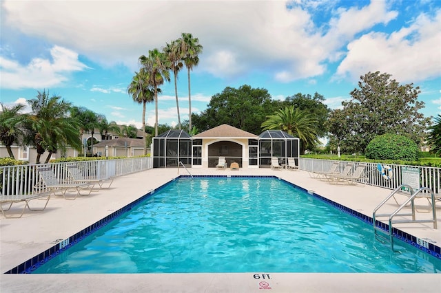 pool featuring glass enclosure, a patio area, and fence