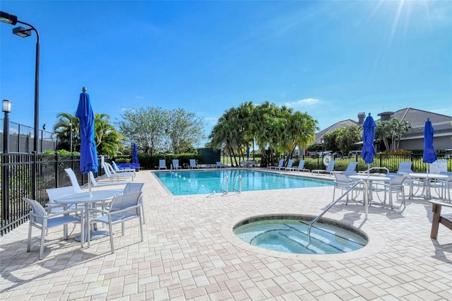 community pool with a community hot tub, fence, and a patio