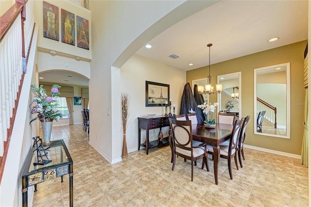 dining room featuring arched walkways, a notable chandelier, visible vents, baseboards, and stairs