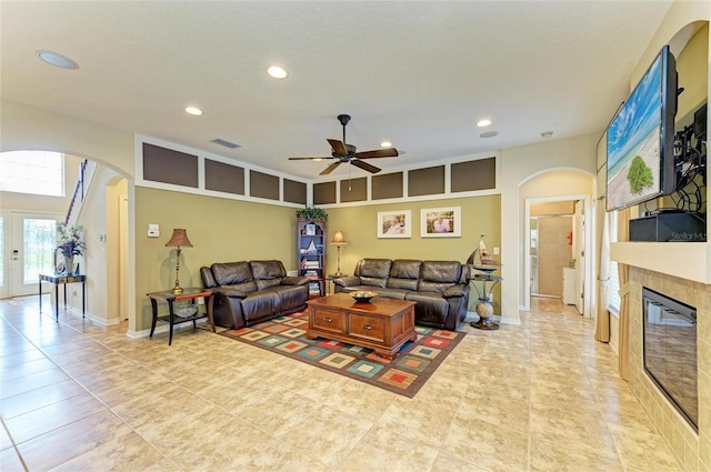 living room with visible vents, arched walkways, a tiled fireplace, and recessed lighting