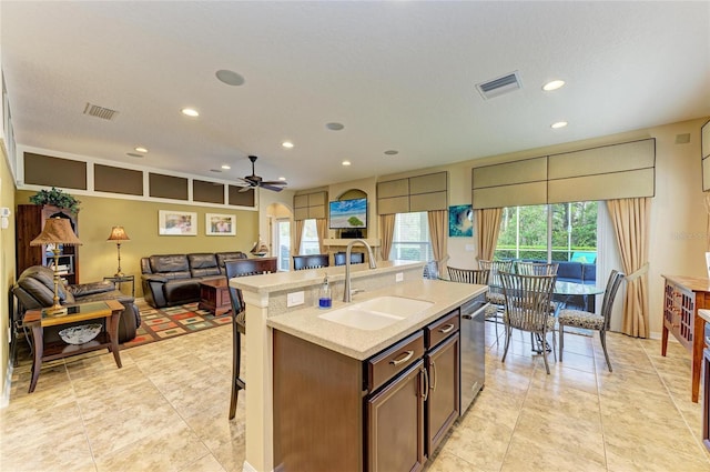 kitchen with a sink, visible vents, light countertops, stainless steel dishwasher, and a kitchen bar