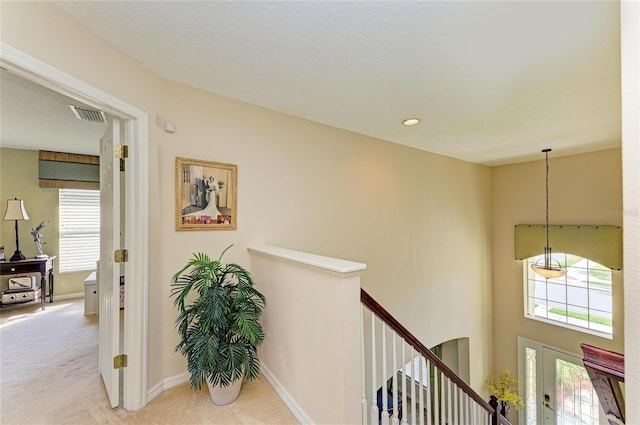 hall featuring visible vents, carpet flooring, an upstairs landing, and baseboards