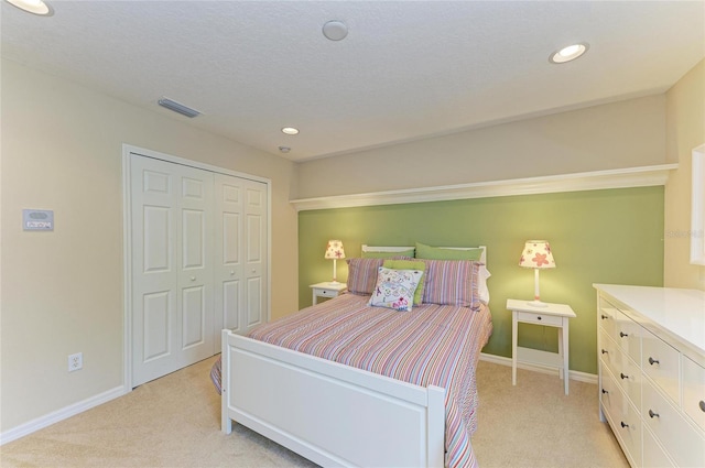 bedroom with baseboards, visible vents, a closet, and light colored carpet