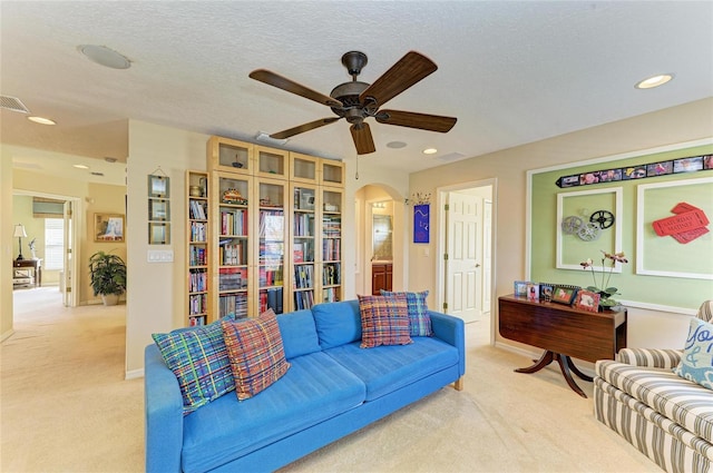 living area with arched walkways, light colored carpet, ceiling fan, a textured ceiling, and recessed lighting