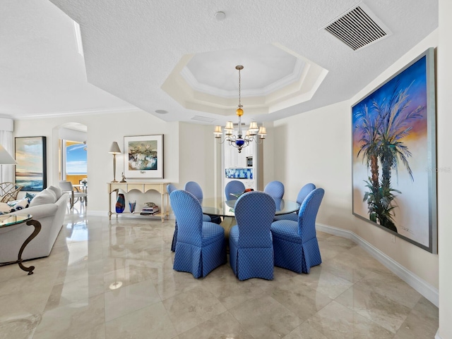 dining room with visible vents, a raised ceiling, an inviting chandelier, and ornamental molding