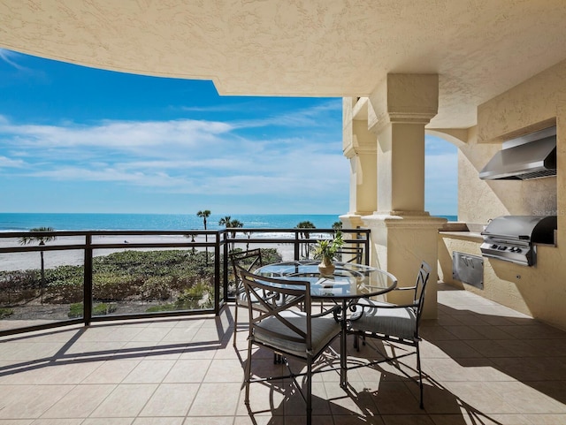 balcony featuring grilling area, a water view, and exterior kitchen