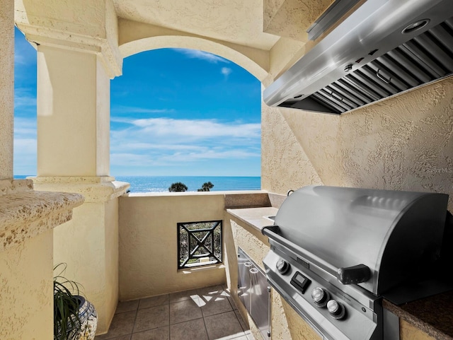 view of patio with area for grilling, an outdoor kitchen, and a water view