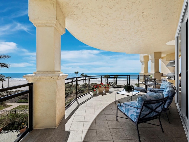 balcony with a beach view, a water view, and a grill