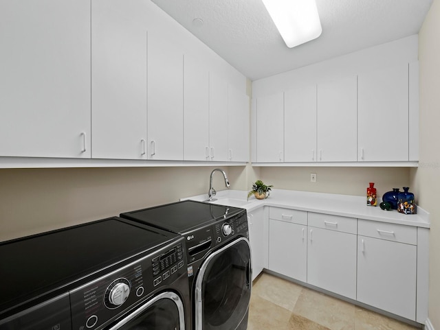 washroom with a sink, a textured ceiling, cabinet space, and washing machine and clothes dryer