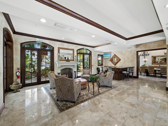 living area with visible vents, french doors, a fireplace, crown molding, and a chandelier