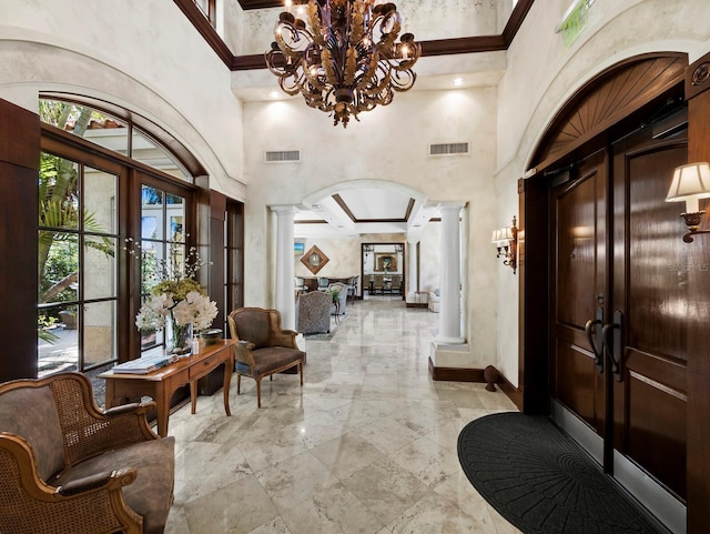 entrance foyer with a notable chandelier, decorative columns, visible vents, and arched walkways