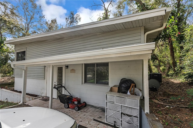 view of front of home with a patio and concrete block siding