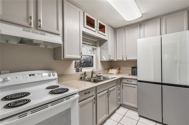 kitchen with white appliances, light countertops, gray cabinetry, under cabinet range hood, and a sink