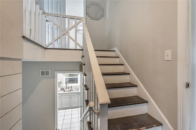 stairs featuring a high ceiling, visible vents, and tile patterned floors