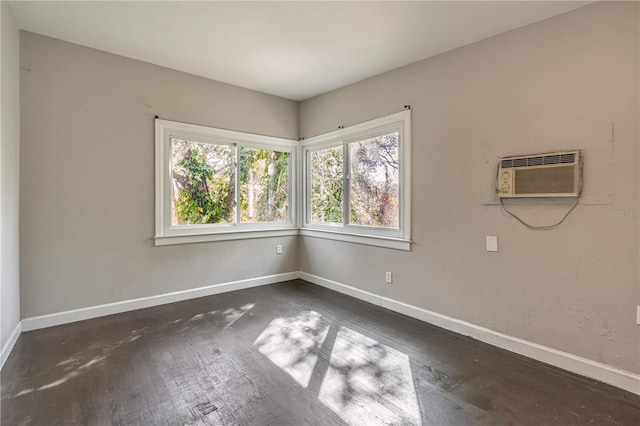 spare room featuring baseboards, wood finished floors, and a wall mounted air conditioner