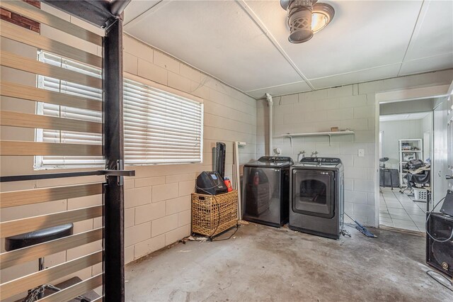 interior space featuring concrete block wall, laundry area, and separate washer and dryer