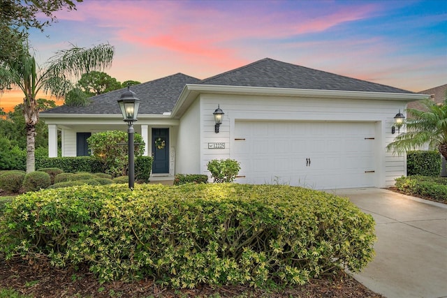 single story home featuring a shingled roof, concrete driveway, and an attached garage