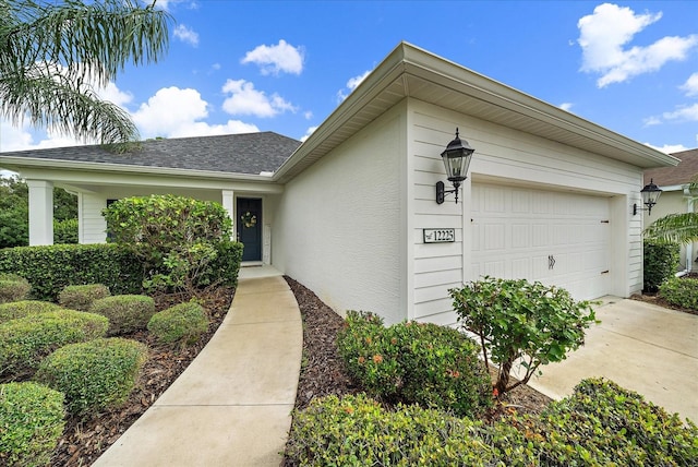 view of front facade with a garage, concrete driveway, a shingled roof, and stucco siding