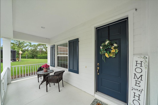 view of exterior entry with a porch and a yard