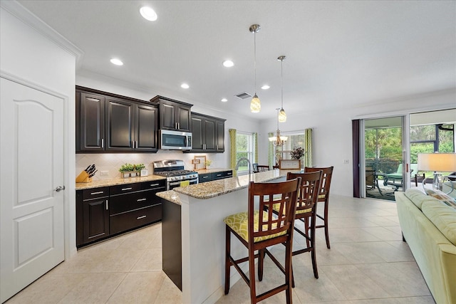 kitchen with stainless steel appliances, a healthy amount of sunlight, a kitchen bar, and decorative backsplash