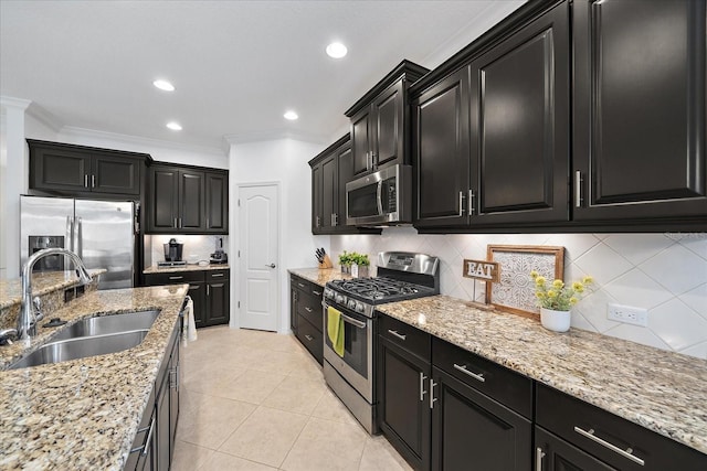 kitchen featuring stainless steel appliances, a sink, dark cabinets, and ornamental molding