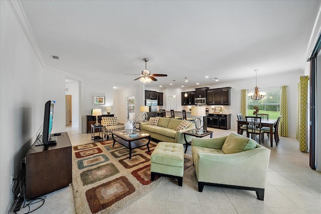 living area featuring light tile patterned floors, recessed lighting, ceiling fan with notable chandelier, visible vents, and crown molding