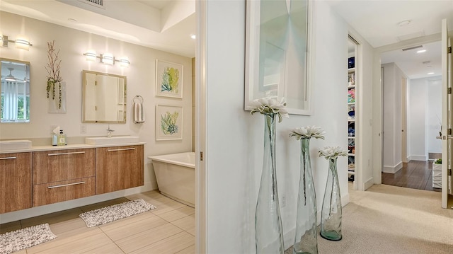 bathroom featuring a freestanding bath, visible vents, a walk in closet, and vanity