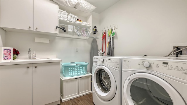 washroom with cabinet space, a sink, washer and clothes dryer, and wood finished floors