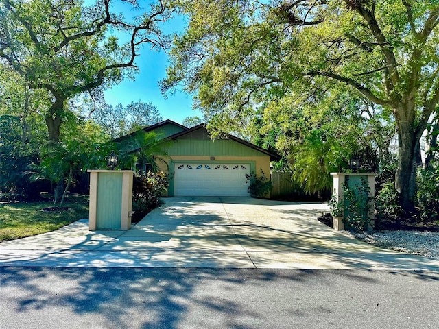 view of front of property with a garage, concrete driveway, and fence