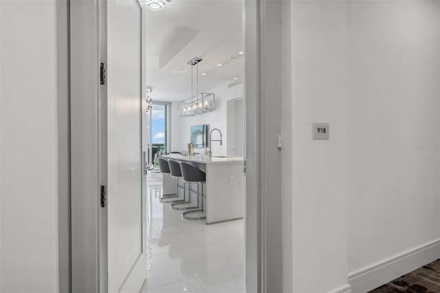 hall with floor to ceiling windows, baseboards, a sink, and recessed lighting