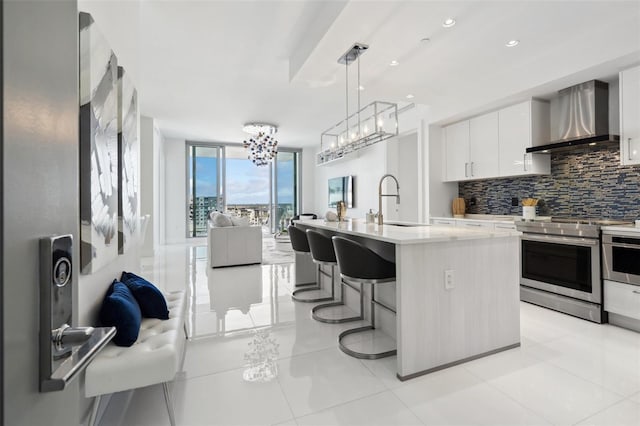 kitchen with decorative backsplash, open floor plan, stainless steel range with electric cooktop, a sink, and wall chimney exhaust hood