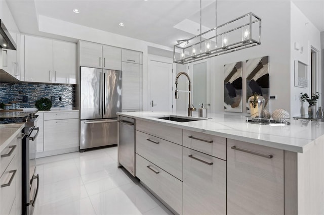 kitchen featuring modern cabinets, light stone counters, a sink, stainless steel appliances, and backsplash