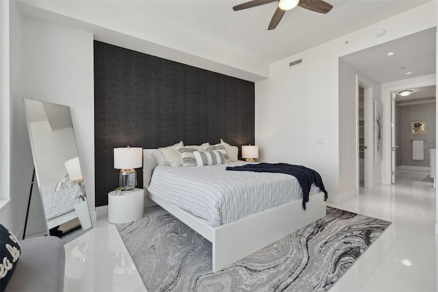 bedroom featuring baseboards, visible vents, ceiling fan, an accent wall, and marble finish floor