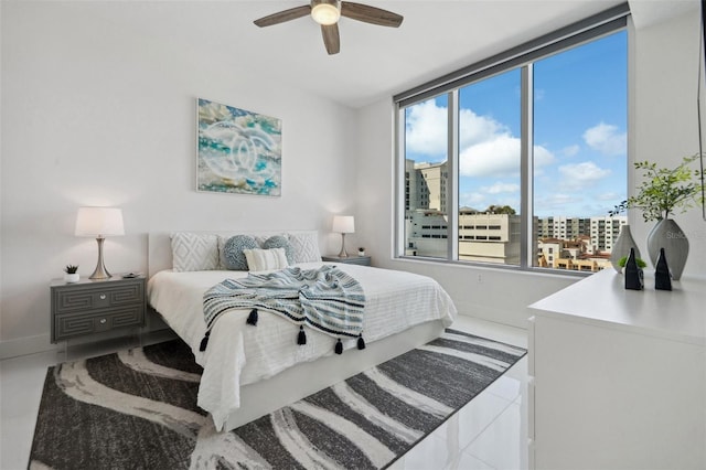 tiled bedroom with a ceiling fan, a city view, and baseboards