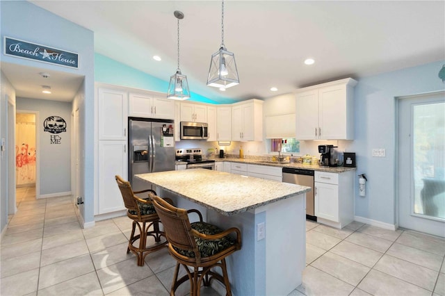 kitchen with white cabinetry, light tile patterned flooring, a kitchen island, and stainless steel appliances