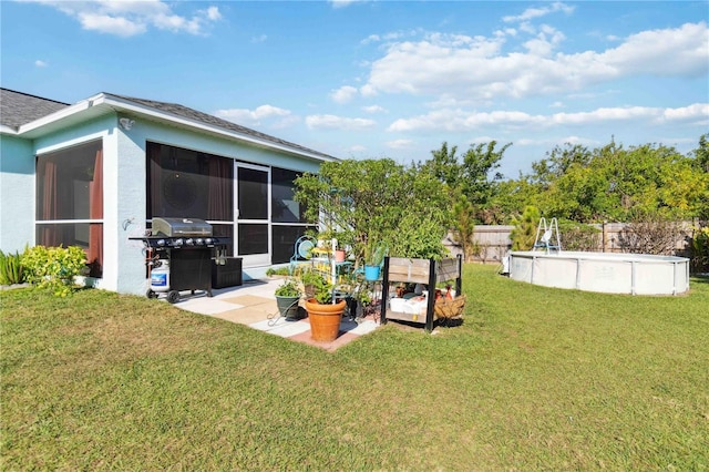 view of yard featuring an outdoor pool, a garden, fence, and a sunroom