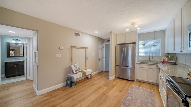 kitchen featuring visible vents, a sink, electric range oven, freestanding refrigerator, and light wood-style floors