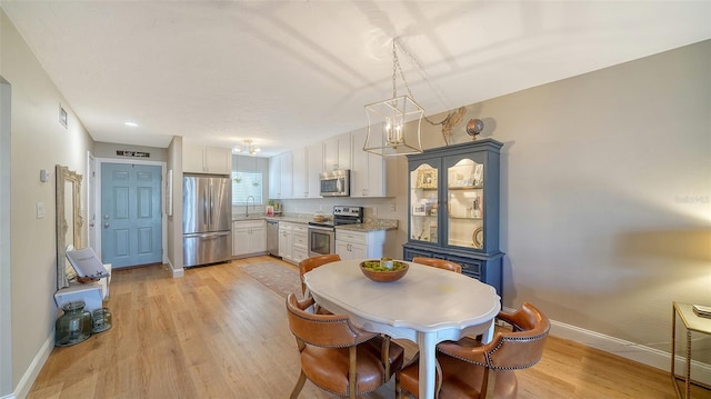 dining room featuring light wood-type flooring, baseboards, and an inviting chandelier