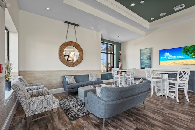 living area featuring a raised ceiling, wood finished floors, visible vents, and ornamental molding