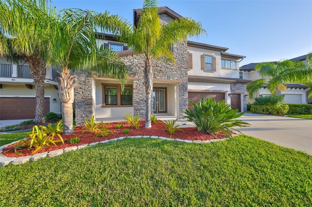 view of front of property featuring driveway, a front yard, stone siding, stucco siding, and an attached garage